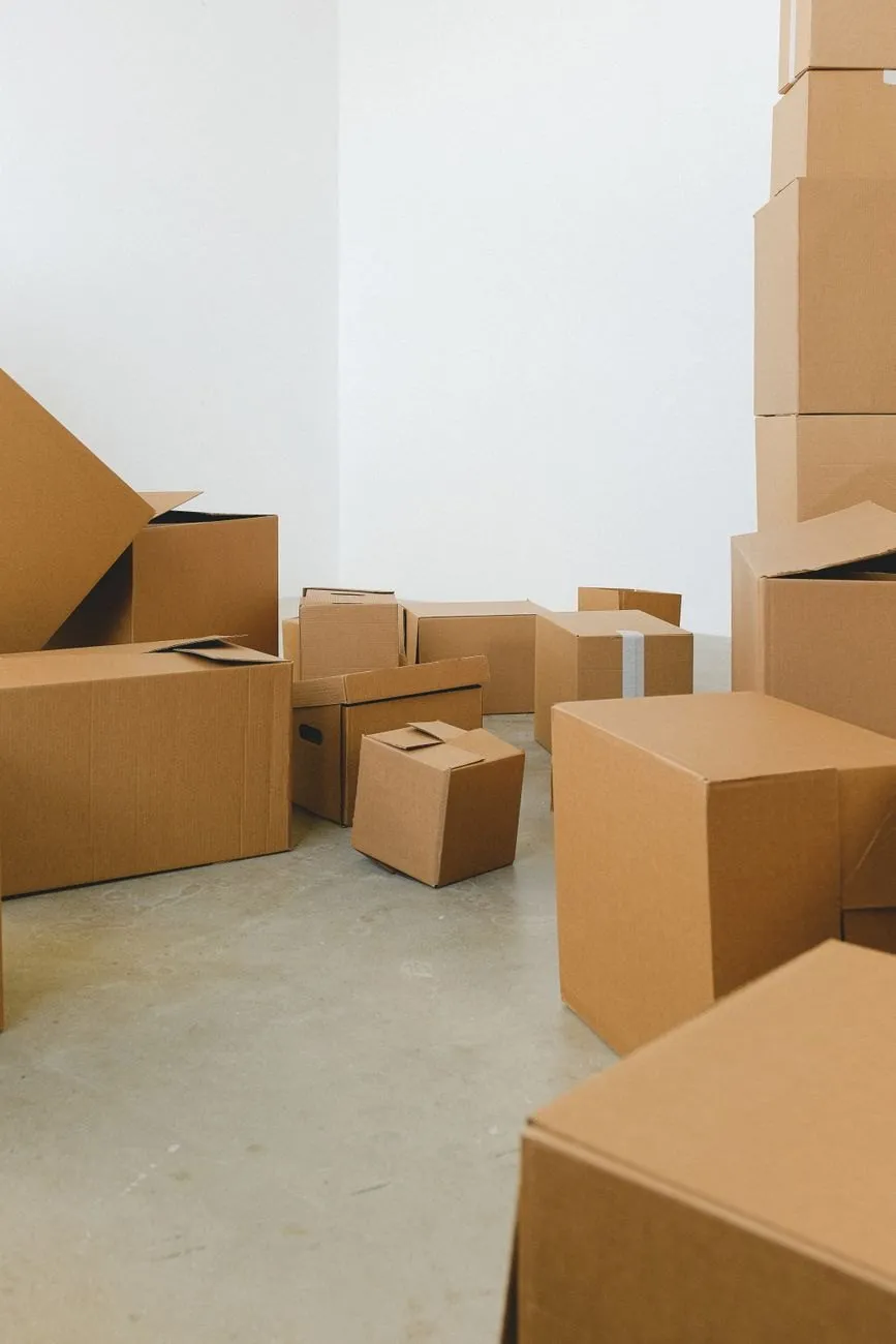 Plain cardboard boxes stacked in an empty white room