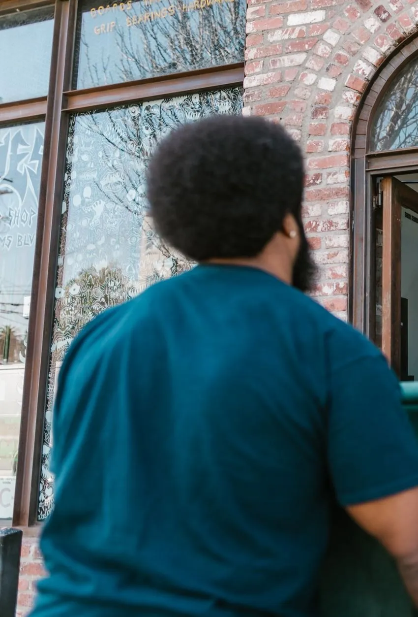 A mover guiding a green sofa through a brick doorway